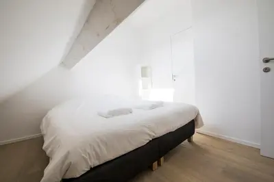 a bedroom with a bed with white sheets and a window at TravelEase - Midi in Brussels