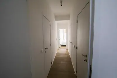 an empty hallway with white walls and wooden floors at TravelEase - Midi in Brussels