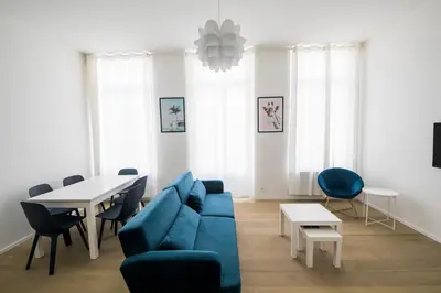 a living room with a blue couch and a table at TravelEase - Midi in Brussels