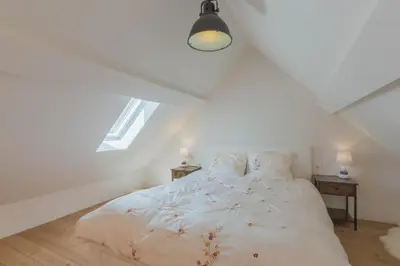 a bedroom with a white bed with two night stands at Cap d'Eau in Waasmunster