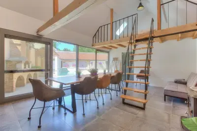 a dining room with a table and chairs and a spiral staircase at Cap d'Eau in Waasmunster