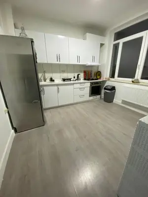 a kitchen with white cabinets and a stainless steel refrigerator at Appartement Deux chambres près de Atomium in Brussels
