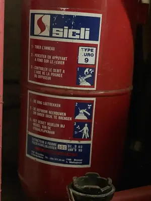 a red fire hydrant with several signs on it at Campe-good in Kampenhout