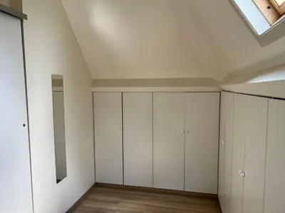 an attic bedroom with white cabinets and a skylight at Appartement29 in Wetteren