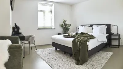 a bedroom with a bed and a table and a chair at B&B Vossebergen Hombeek in Hombeek