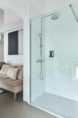 a bathroom with a shower with a couch in it at B&B Vossebergen Hombeek in Hombeek
