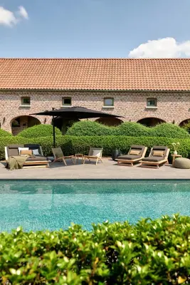 a group of chairs and an umbrella next to a pool at B&B Vossebergen Hombeek in Hombeek