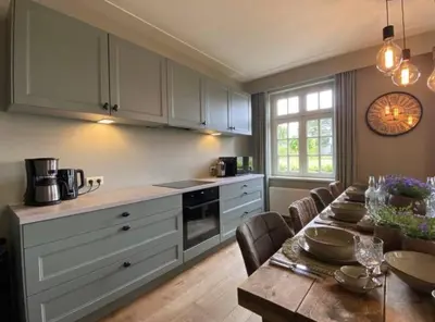 a kitchen with a table and a dining room at Sfeervol familielandhuis in de groene Kempen in Baarle-Hertog