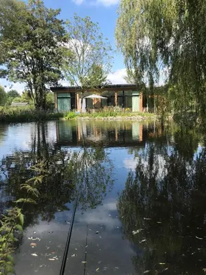 a house in the middle of a lake at Trendy chalet aan visvijver in Hamme