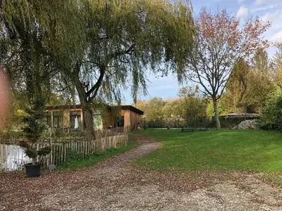 a house in a yard with a tree at Trendy chalet aan visvijver in Hamme