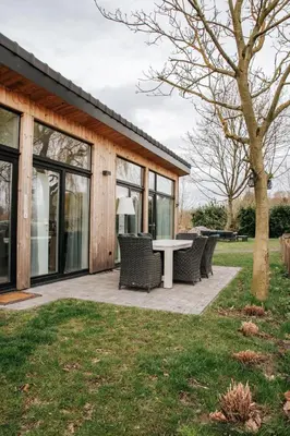 a patio with chairs and a table in front of a house at Trendy chalet aan visvijver in Hamme
