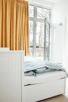 a white bed in a room with a window at Trendy chalet aan visvijver in Hamme