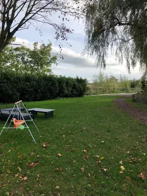 a park with a swing and a picnic table in the grass at Trendy chalet aan visvijver in Hamme