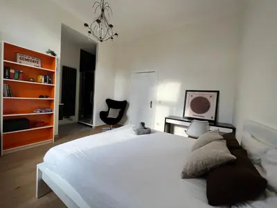 a bedroom with a large white bed and a black chair at Lily Flower - B&B in Kapelle-op-den-Bos