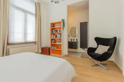 a bedroom with a bed and a chair and a mirror at Lily Flower - B&B in Kapelle-op-den-Bos