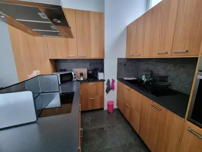 a kitchen with wooden cabinets and a black counter top at BB GUESTHOUSE in Wezembeek-Oppem