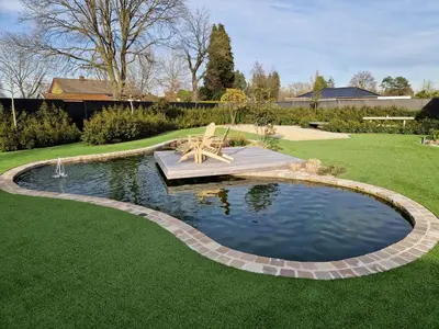 a pond in a yard with a bench in it at Guesthouse Andor in Balen