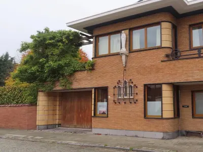 a brown brick house with a wooden door at Authentieke privé-kamer bij Karen in Beveren