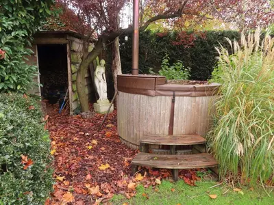 a wooden tub with a bench in a garden at Authentieke privé-kamer bij Karen in Beveren