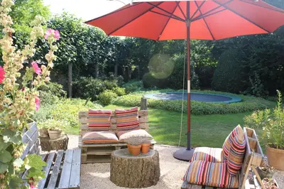 a patio with two chairs and a red umbrella at Authentieke privé-kamer bij Karen in Beveren