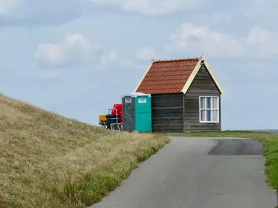 a small house on a hill next to a road at Authentieke privé-kamer bij Karen in Beveren