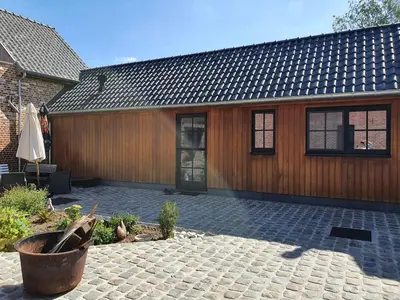 a wooden house with a patio and a building at B&B Dekorn in Pepingen