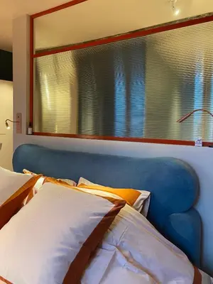 a bed with a blue headboard and a window at Bed & Binnekyk in Mechelen
