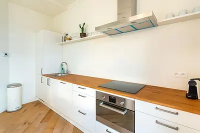 a kitchen with white cabinets and a wooden counter top at Stijlvol duplex appartement in Antwerp