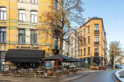 an outdoor cafe with tables and chairs on a city street at Stijlvol duplex appartement in Antwerp