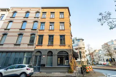 a building on a street with a car parked in front at Stijlvol duplex appartement in Antwerp
