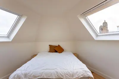 a bed in a room with two windows at Stijlvol duplex appartement in Antwerp