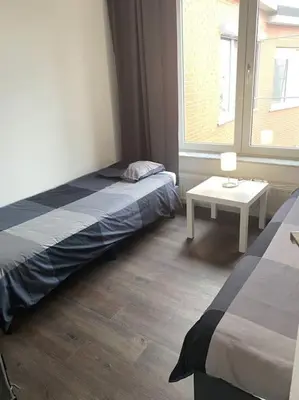 a room with two beds and a table and a window at Beautiful 3 bedroom Apartment in Antwerp
