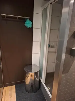 a bathroom with a shower with a trash can and a stool at Loft aan Puyenbroeck in Wachtebeke