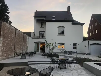 a white building with tables and chairs on a patio at Visite in Evergem