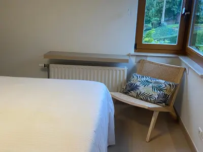 a bedroom with a bed and a chair with a pillow at La Clé des Champs in Tervuren