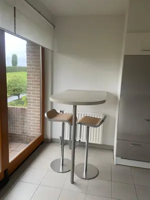a table and two stools in a kitchen with a window at La Clé des Champs in Tervuren