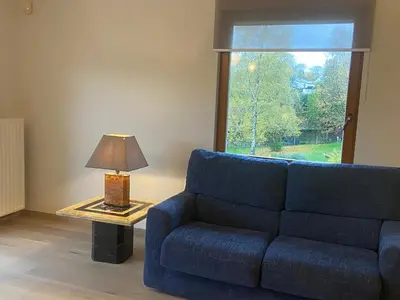 a living room with a blue couch and a table with a lamp at La Clé des Champs in Tervuren