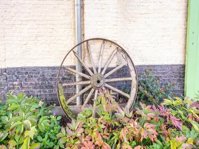 a wooden wagon wheel sitting next to a brick wall at Nice apartment on UNESCO World Heritage Site Wortel-Kolonie in Staakheuvel
