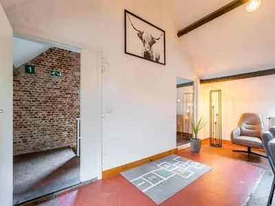 a living room with a chair and a brick wall at Nice apartment on UNESCO World Heritage Site Wortel-Kolonie in Staakheuvel