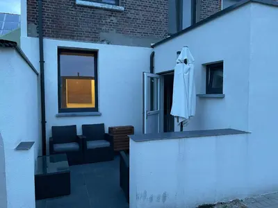 a white building with a chair and an umbrella at House between Antwerp and Brussels in Rumst