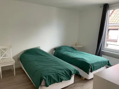 a bedroom with a bed with green sheets and a window at House between Antwerp and Brussels in Rumst