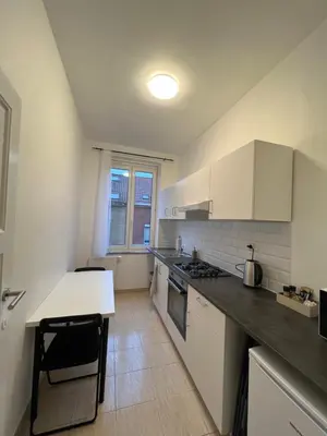 a kitchen with white cabinets and a counter top at Cosy Apartment Merode 2 in Brussels
