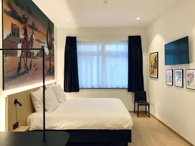 a bedroom with a bed and a chair and a window at Comic Art Hotel in Ghent