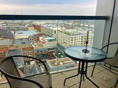 a table on a balcony with a view of a city at London Tower Apartments - Antwerp in Antwerp
