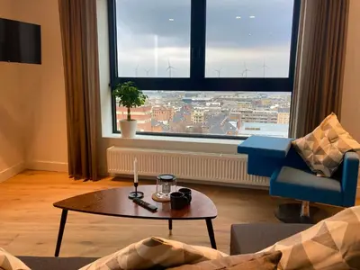 a living room with a table and a large window at London Tower Apartments - Antwerp in Antwerp