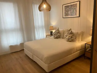 a bedroom with a white bed and a chandelier at London Tower Apartments - Antwerp in Antwerp