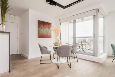 a dining room with a table and chairs and a large window at London Tower Apartments - Antwerp in Antwerp