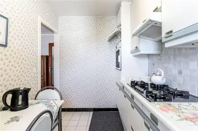 a white kitchen with a stove and a sink at SUPERB FLAT WITH 3 BEDROOMS PARKING AND BALCONy in Antwerp