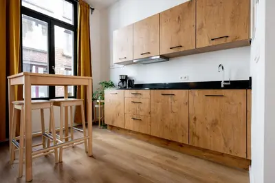 a kitchen with wooden cabinets and a wooden stool at Miniloft Pelgrim in Antwerp