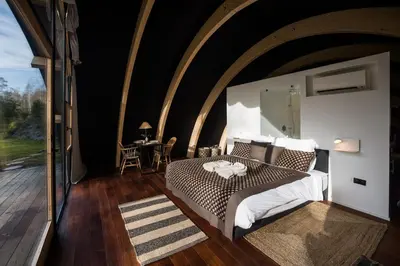 a bedroom with a bed and a large window at Room8 luxury glamping in Huldenberg